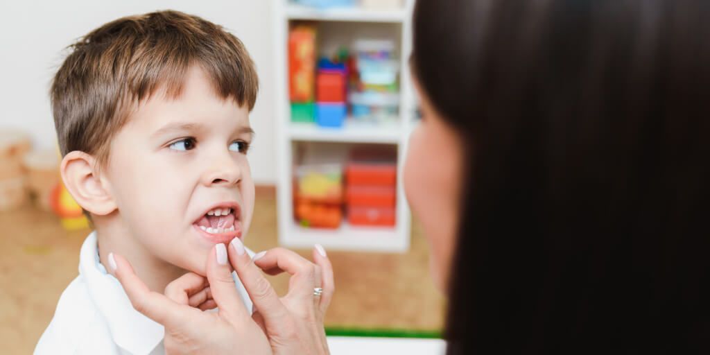 Logopeda evaluando a un frenillo de la lengua a un niño Logopeda evaluando a un niño para determinar si es necesario cortar frenillo lengua
